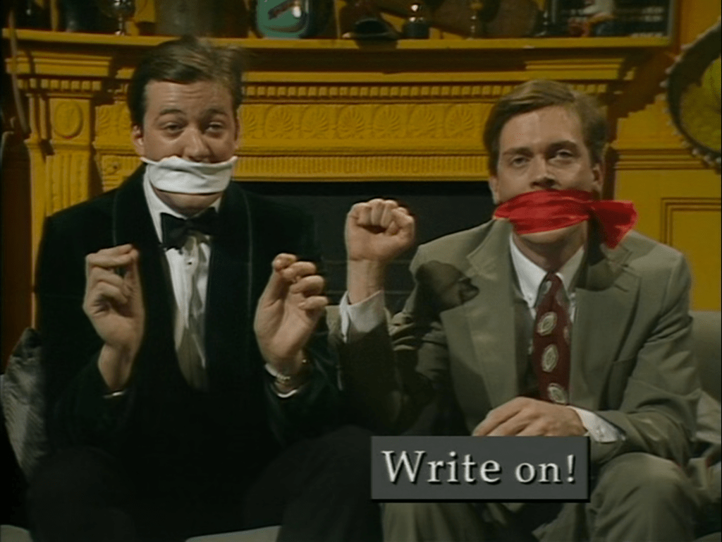 Two men sit on a couch. They are wearing suits, and gags over their mouths. The man on the right has his fist raised, and a caption underneath reads: "Write on!" (with a w).