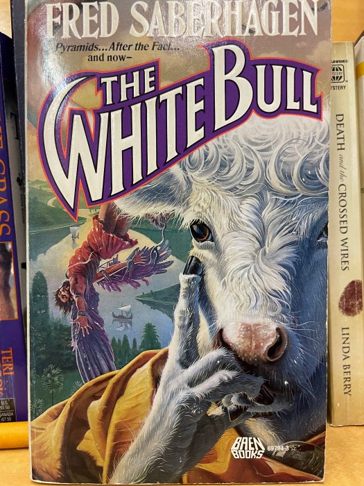 The cover of The White Bull by Fred Saberhagen. Pictures an anthropomorphised white bull with his right hand curled under his chin, index finger pointing up toward his eye. He has fingers but the fingers look like bull legs, i.e. they're covered in fur and the knuckles look like knees and the fingertips are hooves.