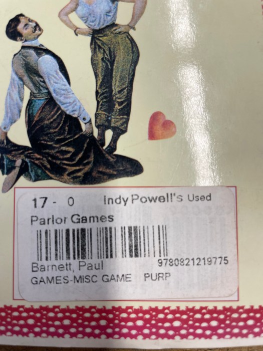 The back cover of the book Parlor Games: Traditional Indoor Games to Amuse and Delight. A mustachioed Victorian gentlemen is kneeling with has back to us, he has his jacket off and instead is wearing a long brown dress. His hands hold the skirt of the dress while he tilts his head back toward us with what could best be described as a saucy smile. A woman wearing just a shift tucked into pants (bloomers?) is leaning over him with her hands on her hips. Also there's a heart in the corner (cartoon heart, not anatomically correct heart.)